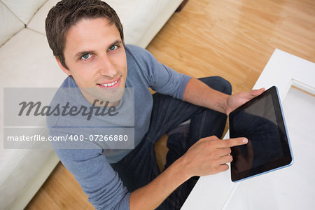 Overhead portrait of a young man using digital tablet in living room at home