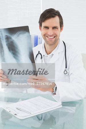 Portrait of a smiling male doctor with lungs x-ray in the medical office