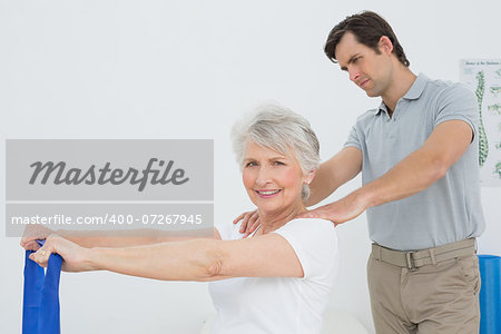 Male therapist assisting senior woman with exercises in the medical office