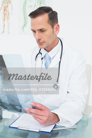 Concentrated male doctor looking at x-ray picture in the medical office