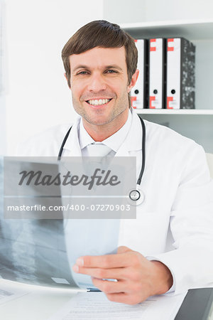 Portrait of a smiling male doctor with x-ray picture of spine in the medical office