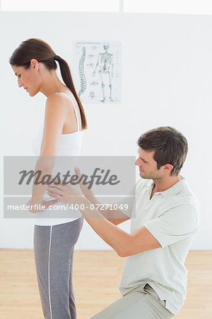 Side view of a male physiotherapist examining woman's back in the medical office