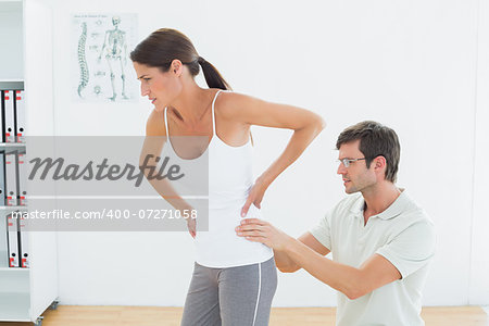 Side view of a male physiotherapist examining woman's back in the medical office