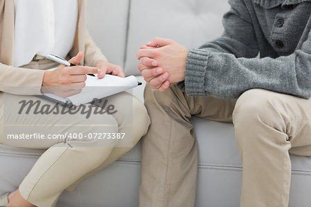 Closeup mid section of a financial adviser writing notes with man at home