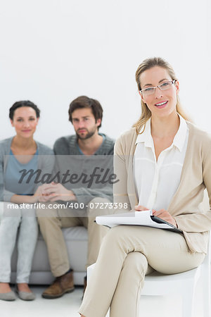 Portrait of a female financial adviser with young couple in background at home