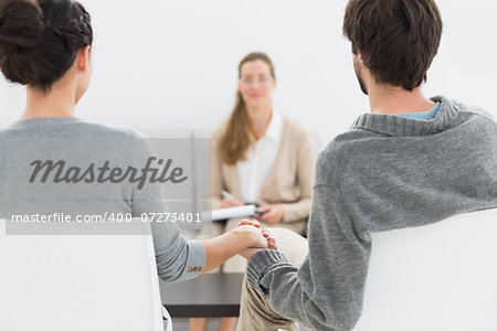 Blurred female financial adviser in meeting with young couple at home