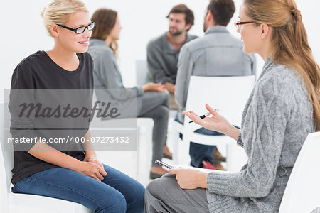 Group therapy session in circle with therapist and client in foreground