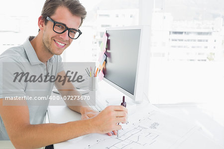 Side view of a smiling young man using compass on design