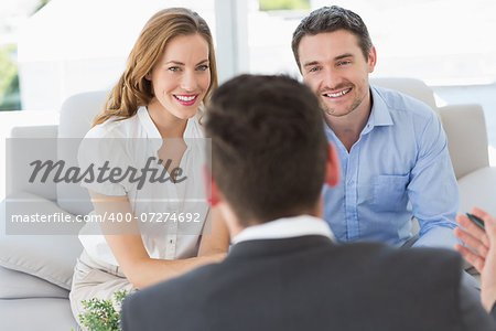 Smiling young couple in meeting with a financial adviser at home