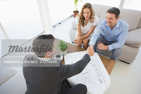High angle view of a smiling young couple in meeting with a financial adviser at home