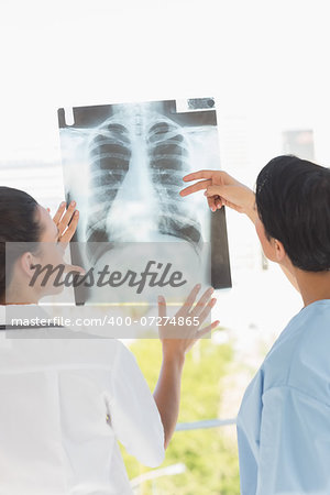 Rear view of two female doctors examining xray in the medical office