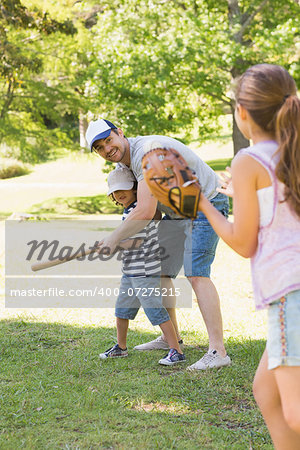 Family of three playing baseball in the park