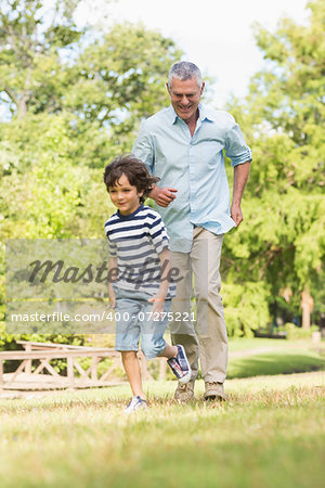 Full length of a grandfather and son running on grass in the park