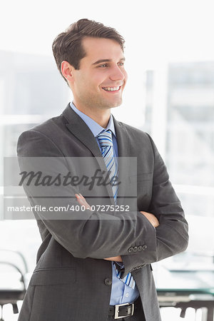 Handsome smiling businessman with arms crossed in the office