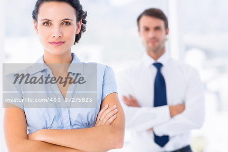 Portrait of a young businesswoman with arms crossed smiling in a bright office