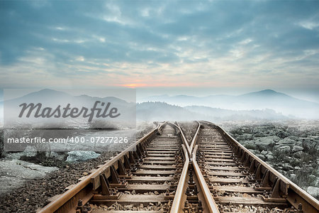 Railway tracks leading to misty mountains