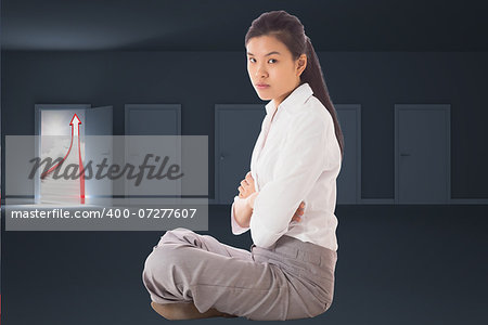 Businesswoman sitting cross legged with arms crossed against door opening to show red arrow and sky