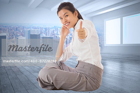 Businesswoman sitting cross legged showing thumb up against city scene in a room