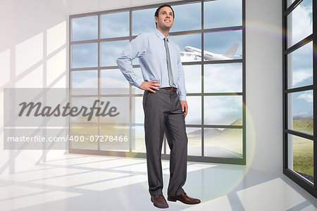 Smiling businessman with hand on hip against airplane flying past window