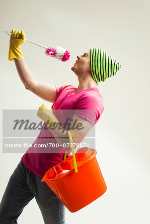 Young man having fun with colorful cleaning supplies, studio shot on white background