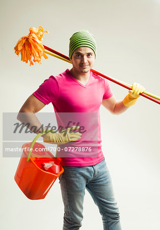 Portrait of young man holding colorful cleaning supplies, studio shot on white background Portrait of young man holding colorful cleaning supplies, studio shot on white background