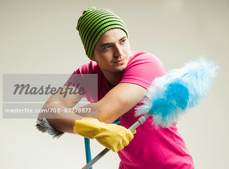 Close-up portrait of young man with colorful cleaning supplies, studio shot on white background