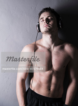 Portrait of young man wearing headphones and listening to music, studio shot on grey background