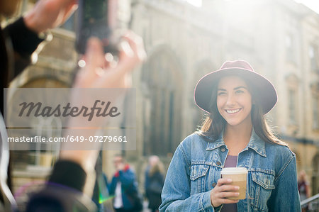 Man photographing young woman in hat