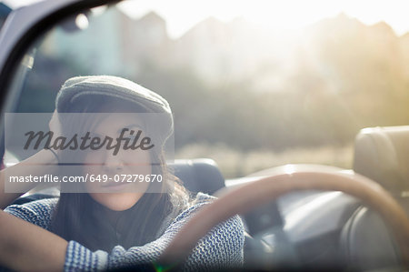 Young woman wearing flat cap in convertible