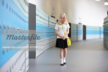Unhappy schoolgirl walking alone in school corridor