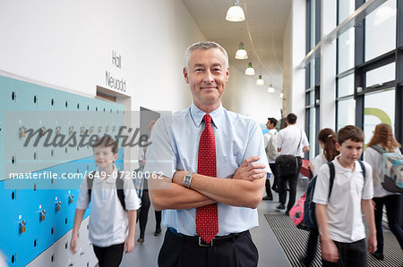 Portrait of male teacher with arms folded in school corridor