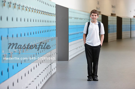 Portrait of schoolboy with hands in pockets in school corridor