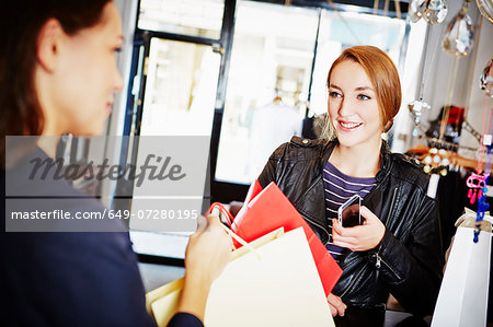 Young women in shop with shopping bags and smartphone