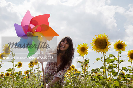 Woman holding windmill in field of sunflowers