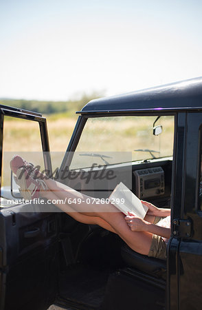 Mid adult women sitting in car reading book