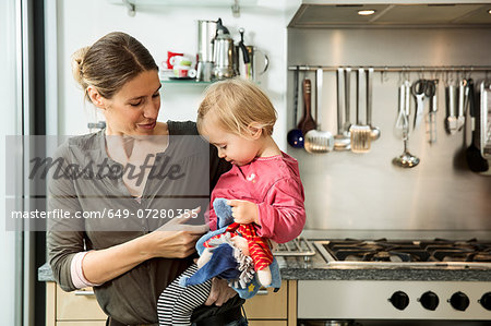 Mother carrying baby girl in kitchen