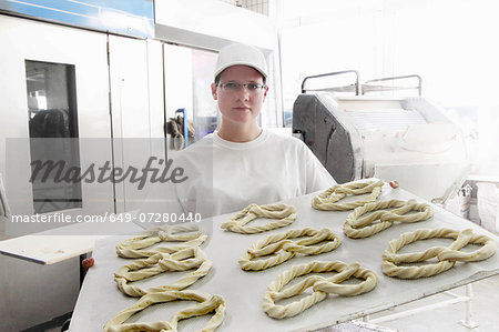 Baker holding baking sheet of pretzels