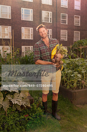 Mid adult man with harvested beetroot on council estate allotment