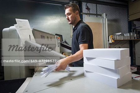 Worker disposing of paper trimmings in print workshop