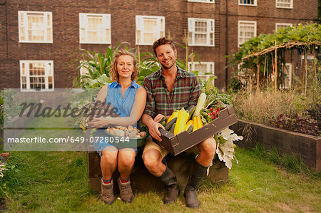 Couple holding harvested vegetables on council estate allotment Couple holding harvested vegetables on council estate allotment
