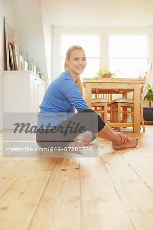 Young woman sitting on floor wearing sports clothing