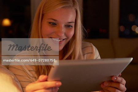 Young woman sitting on sofa, using digital tablet
