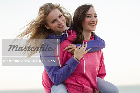 Two young female friends having fun on beach, Whitstable, Kent, UK