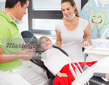 Girl in dentists chair with dentist and dental nurse
