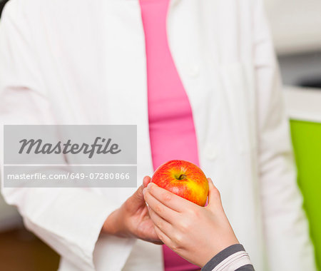 Dentist giving girl apple, close up