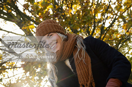 Smiling young woman wrapped up in autumnal park