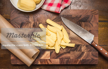 Still life of peeled and sliced potatoes, kitchen knife on chopping board