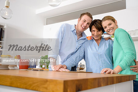 Portrait of youthful grandmother with adult grandchildren in kitchen