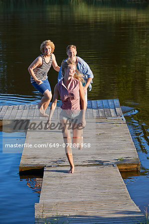 Three young adult friends running on pier, Gavle, Sweden