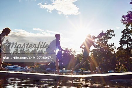 Three adult friends running along pier, Gavle, Sweden